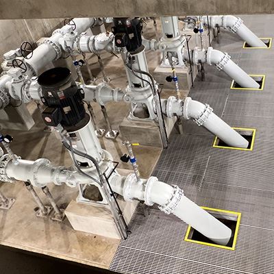 An overhead view of a room with four large pipes going through grates in the floor